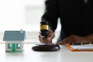 Probate Lawyer judges' gavel in hand with a model of house on the table